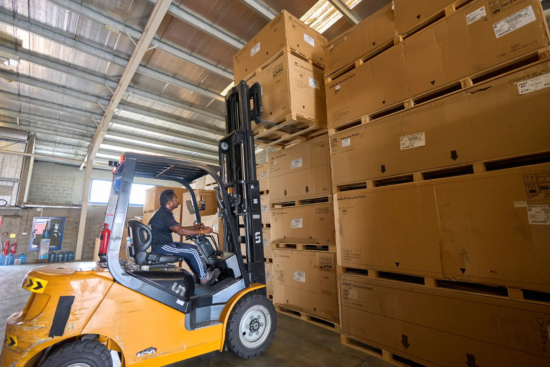 Forklift with its mast raised, stacking large export crates high in the Dubai warehouse